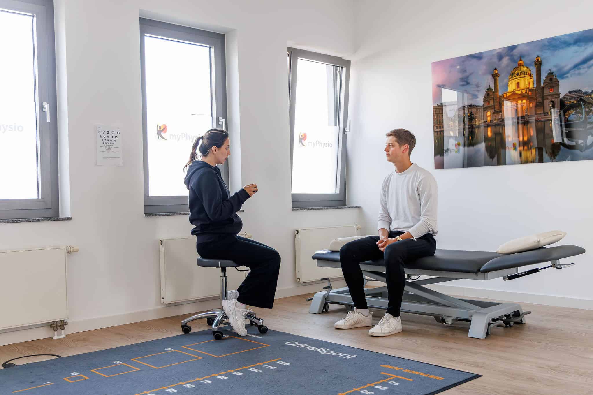 Physiotherapie-Übung bei myPhysio Deutschland: Eine ältere Frau führt mit Unterstützung ihres Physiotherapeuten eine Übung mit einem Theraband durch.